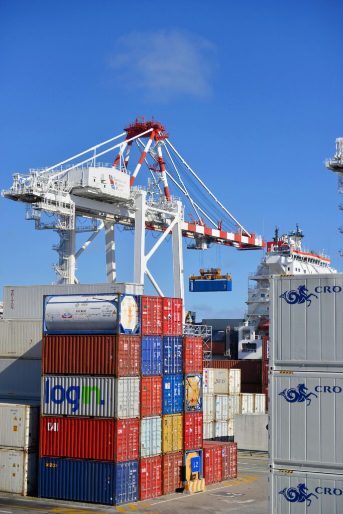 pexels-photo-1624695-1624695 Colorful shipping containers stacked in a busy port with cranes overhead.